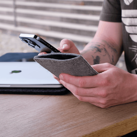 Stylishe Handytasche in hellgrau Filz für Google Pixel 10, gehalten von einer Person an einem Tisch.
